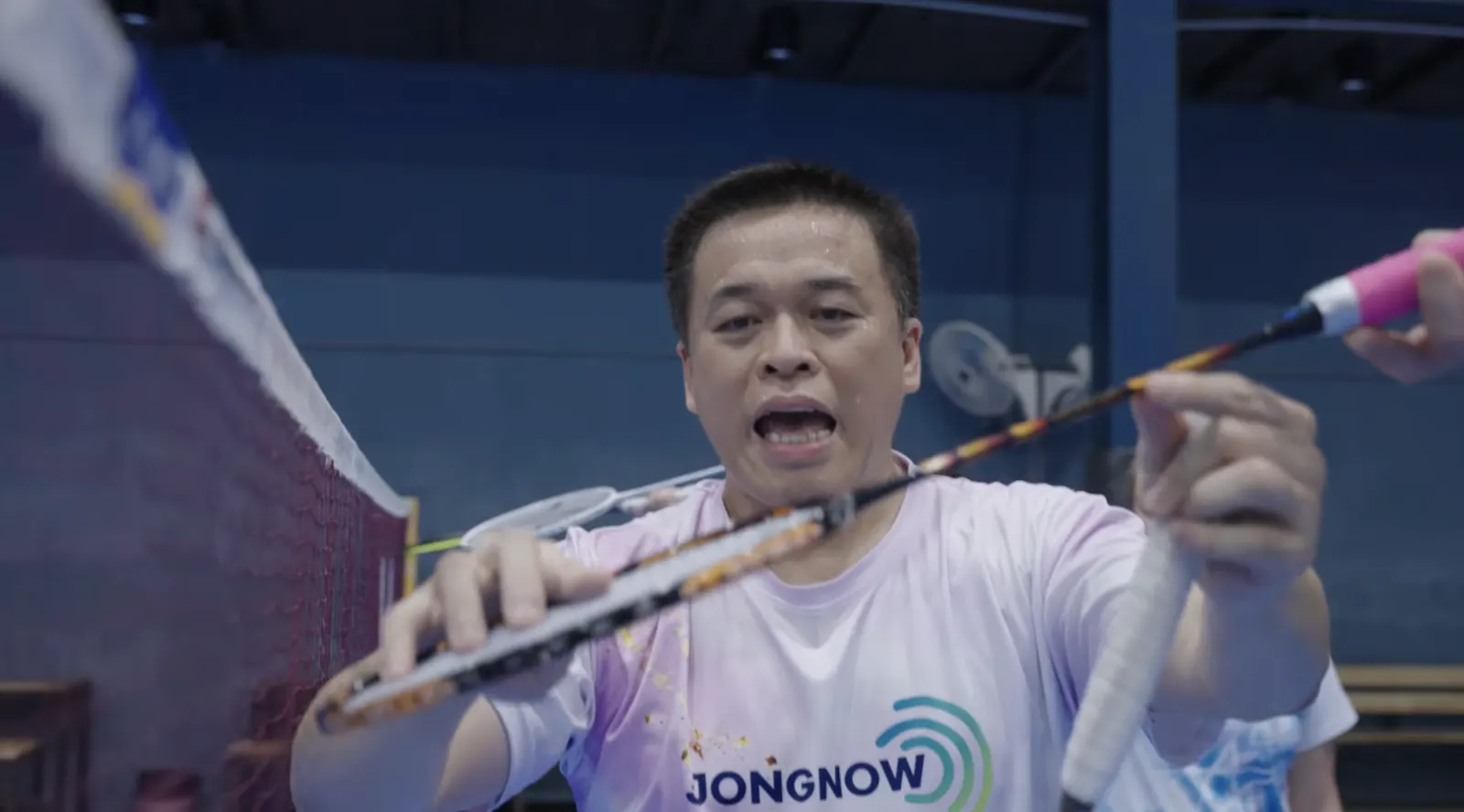 Coach thaïlandais corrigeant le geste d’un stagiaire pendant un stage de badminton adulte