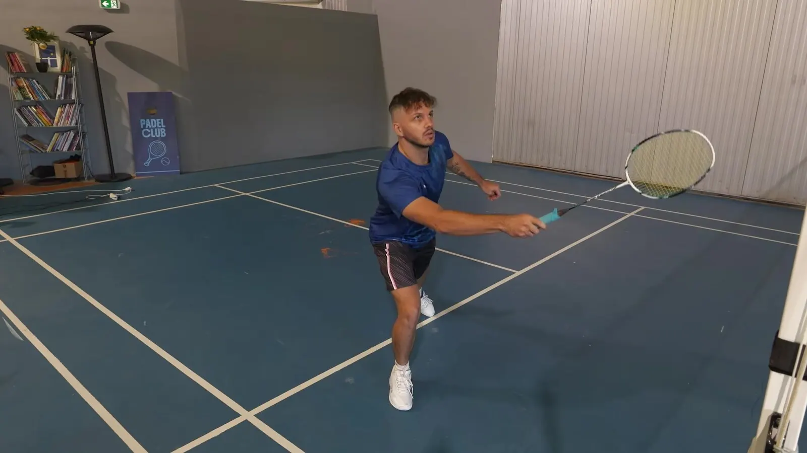 Richard Badminton en fente vers l'avant, raquette tendue pour toucher le volant pendant son déplacement