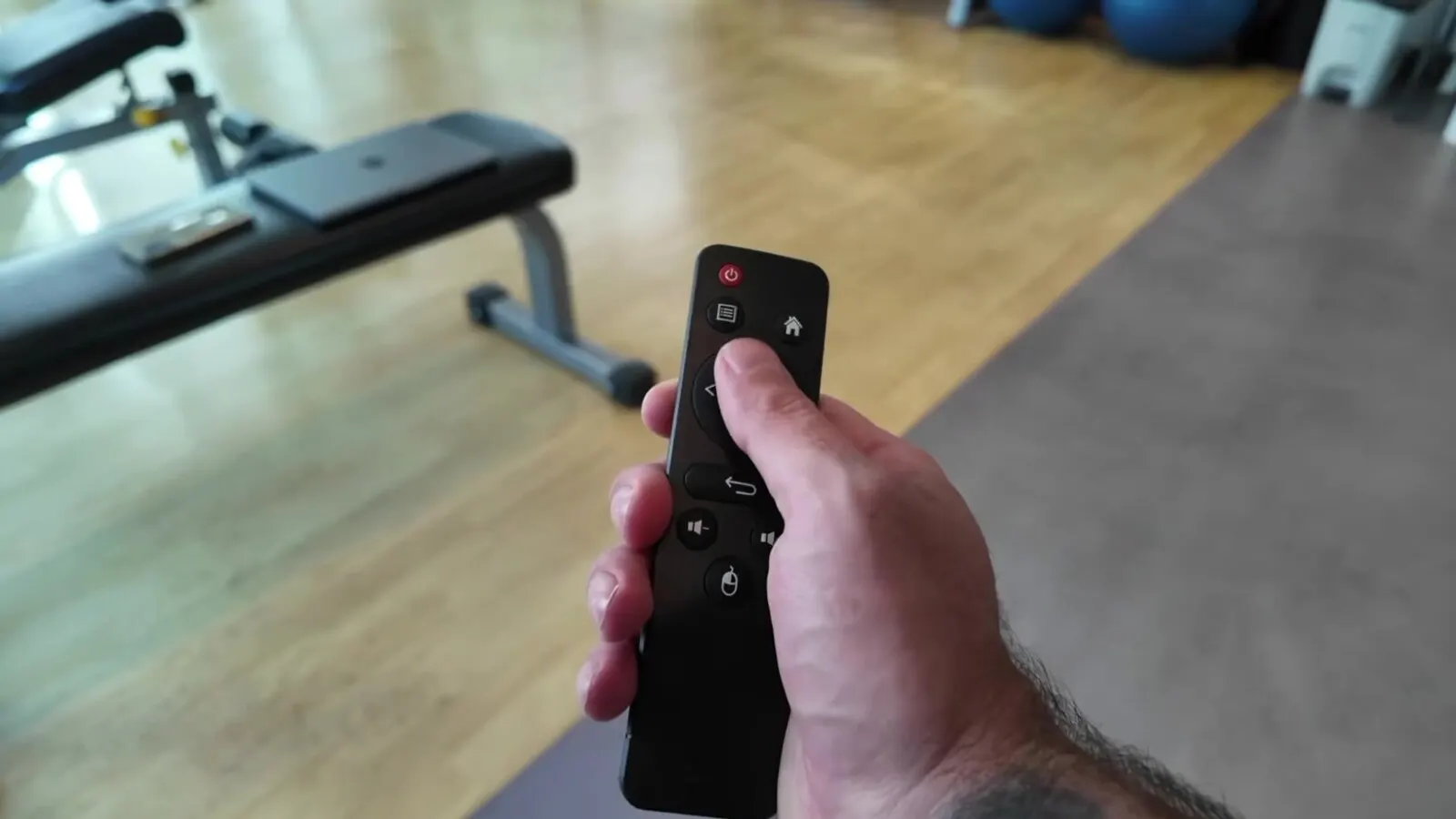 Main qui tient une télécommande, pouce posé sur le bouton, l'image à garder en tête pour la prise revers