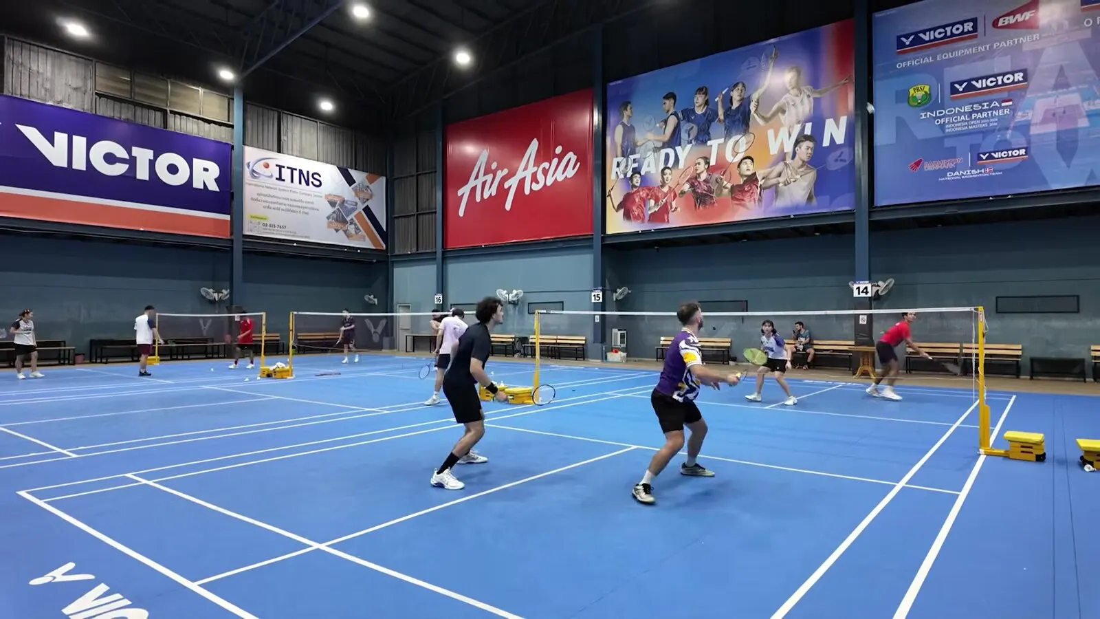 Partie de double sur un court bleu, situation où la paire en défense doit renvoyer loin des adversaires