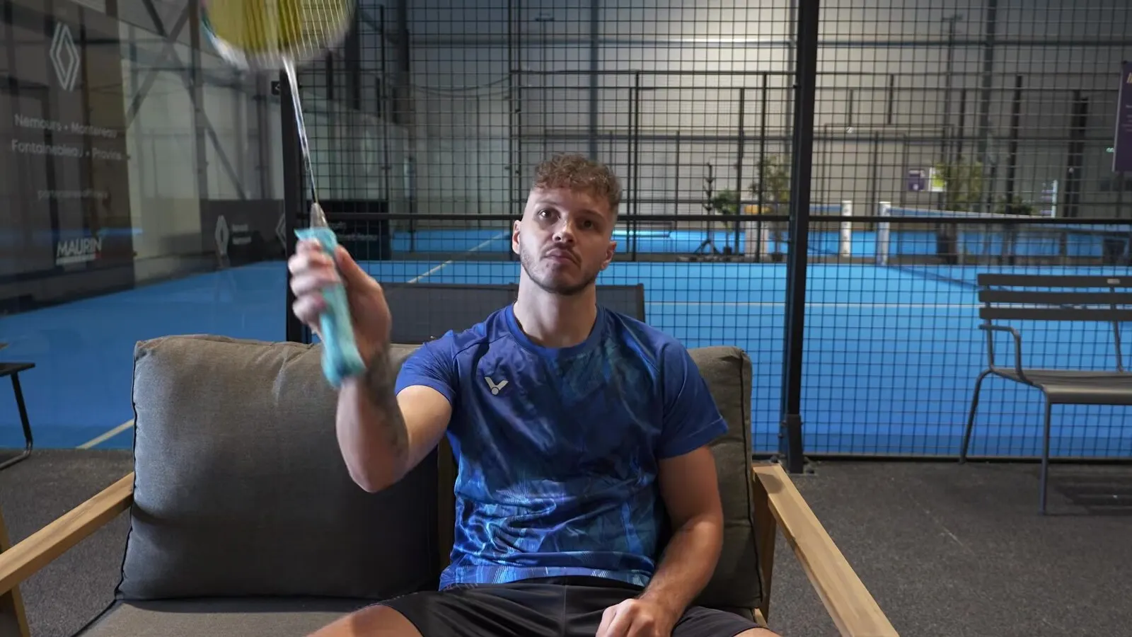 Richard assis dans un fauteuil, raquette levée, qui travaille ses changements de prise sans terrain