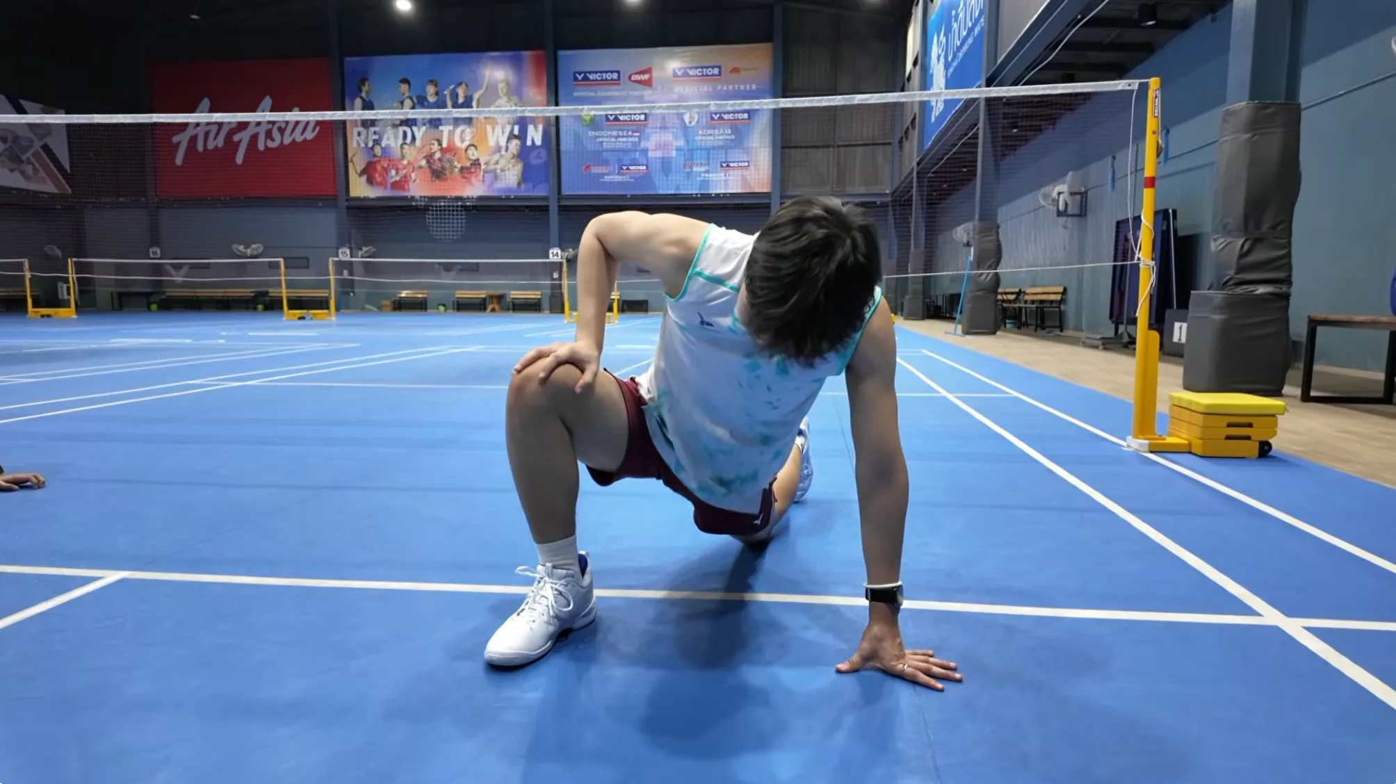 Échauffement badminton étape 1 : déverrouillage articulaire au sol sur un terrain de badminton
