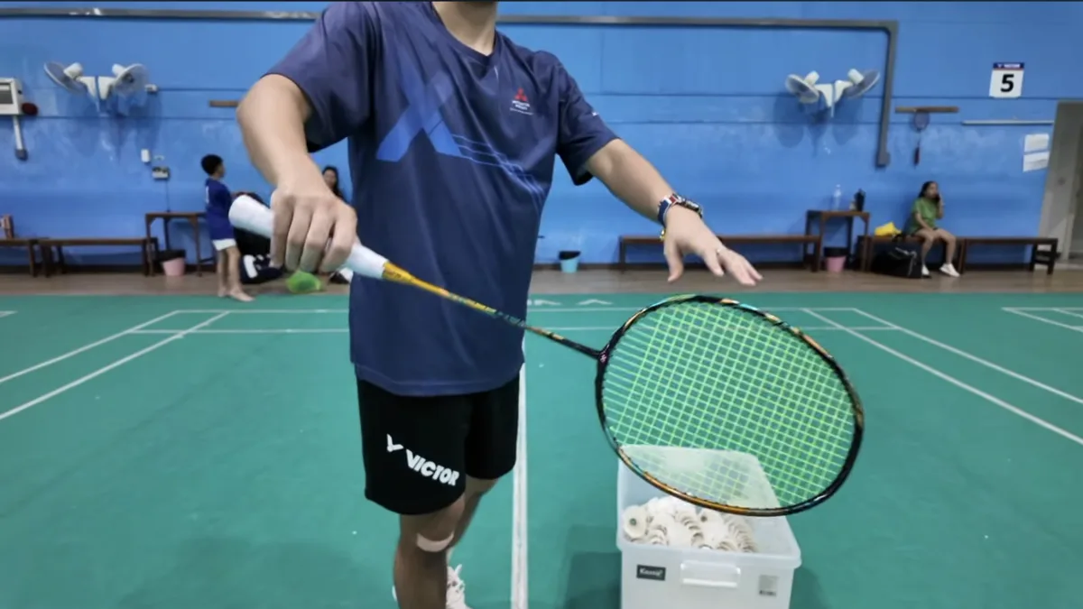 Positionnement de la raquette à 45 degrés pour le service revers au badminton, bras à distance idéale du corps