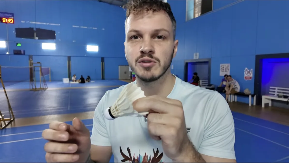 Comment tenir le volant de badminton avec le pouce, l'index et le majeur, positionné directement au contact du tamis de la raquette