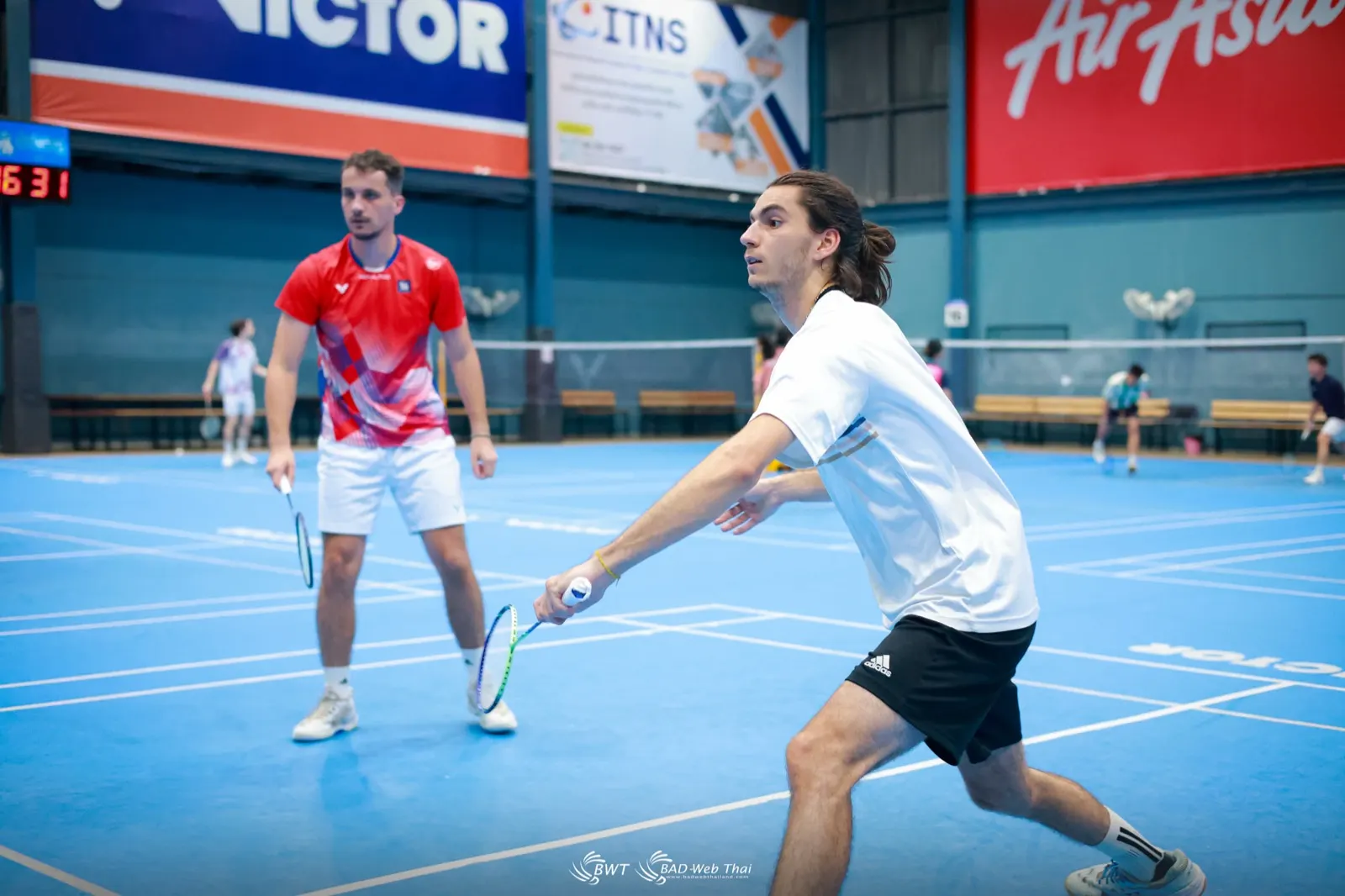 Stagiaire en fente pour défendre en double pendant un entraînement de badminton à la Ponsana Académie de Bangkok