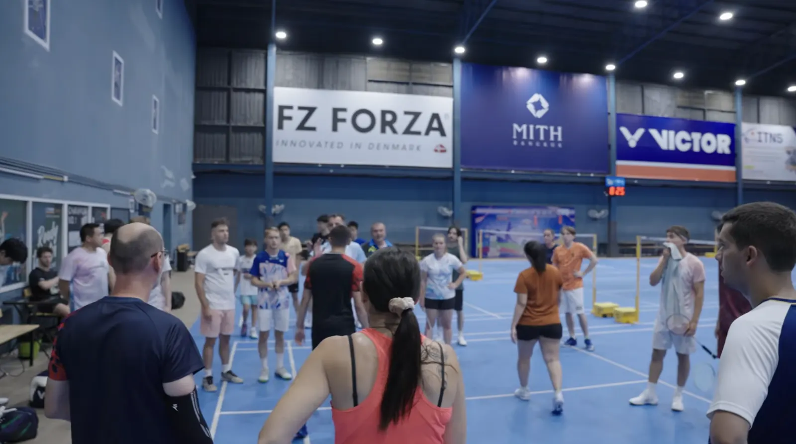 Stagiaires réunis autour du coach pendant un entraînement du stage de badminton à Bangkok
